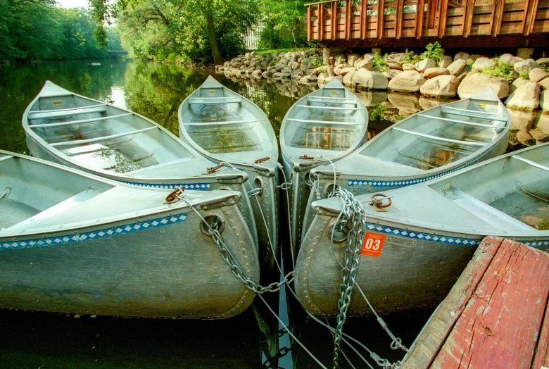 three canoes tied to dock next to a body of water