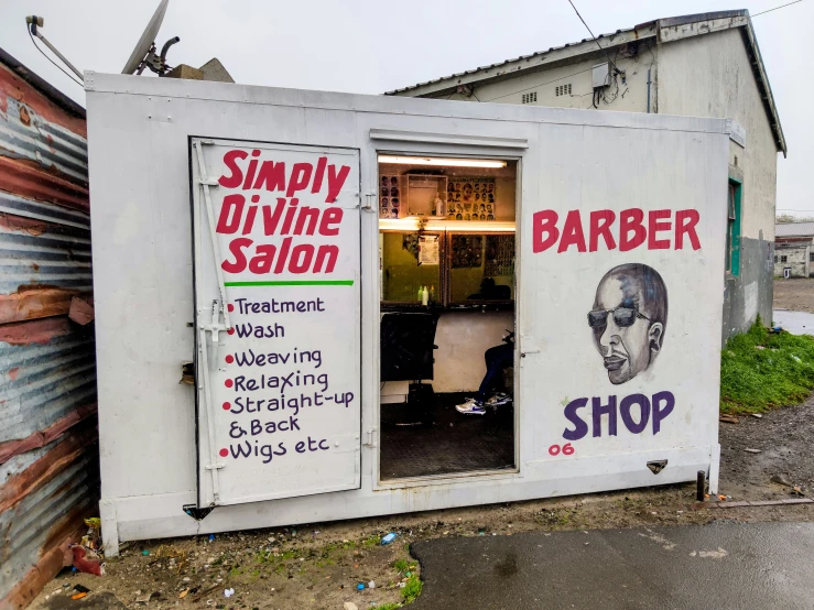 a barber shop sitting next to a metal building