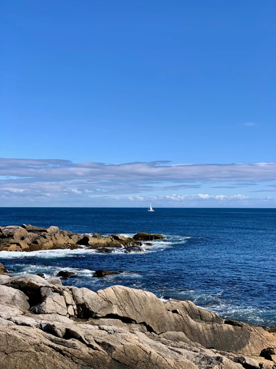 an image of a sailboat going past some rocks