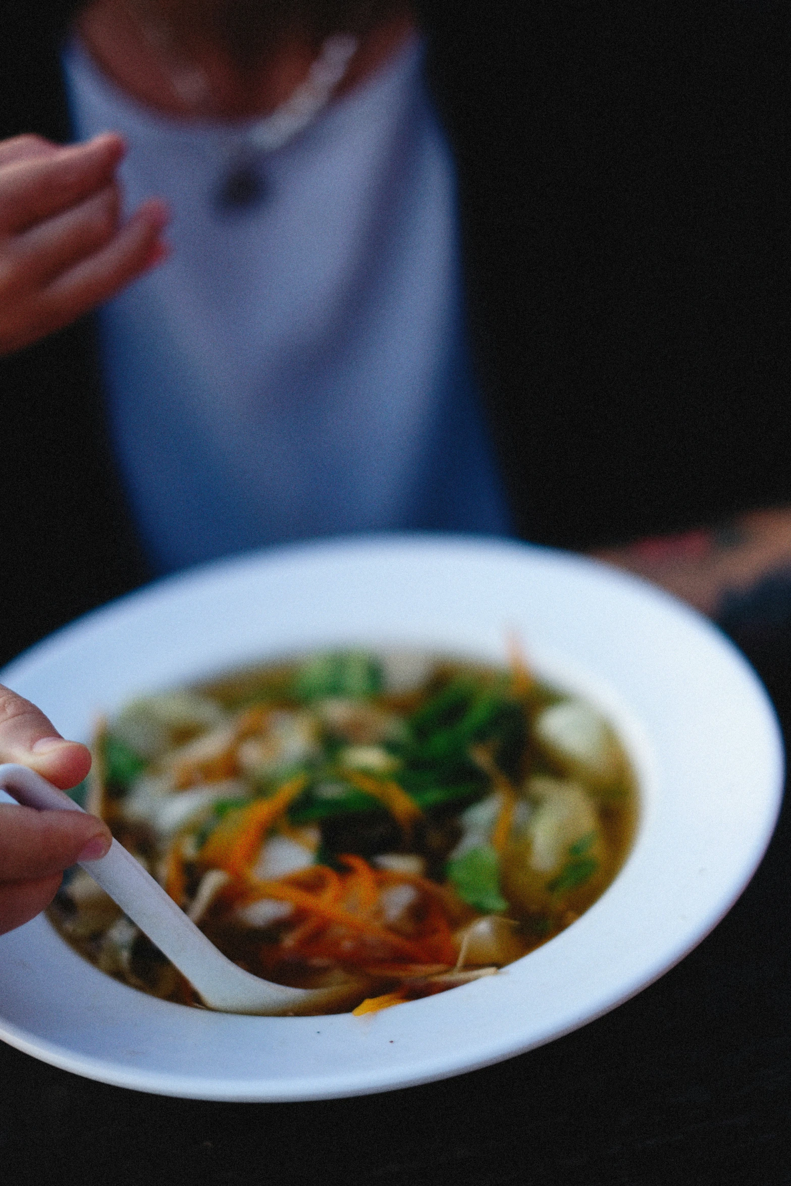 a plate with soup, and someone eating from a bowl