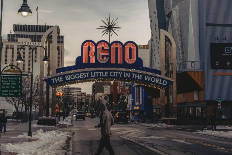 a man walking down a snowy road in front of a neon sign