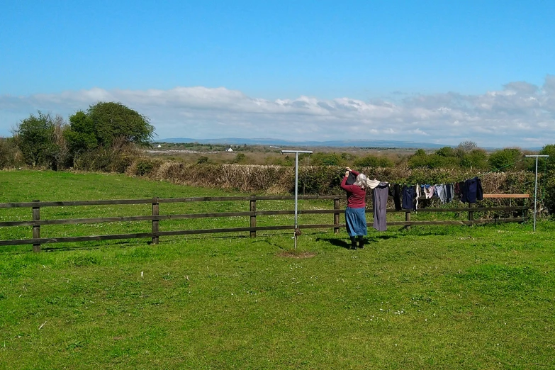 a man looking over a wooden fence with clothes hanging outside