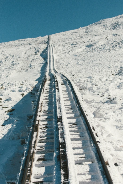two train tracks going up the side of a snowy mountain