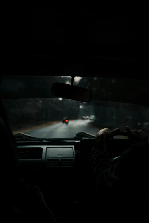 a person driving on a dark road with red lights