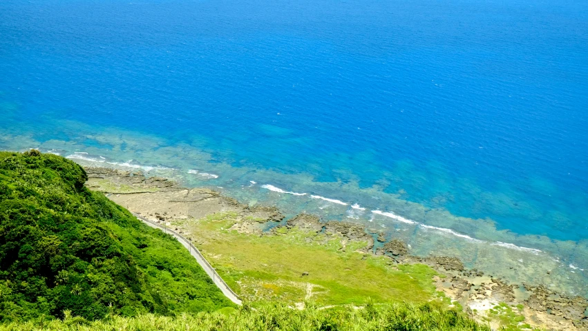 an area with grass, water, and mountains near the ocean