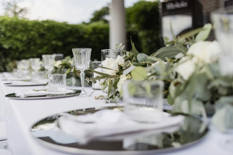 long table with many glass dishes with floral centerpieces