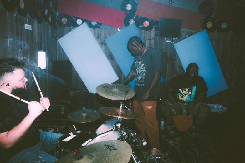 a man playing drums while another mans watches