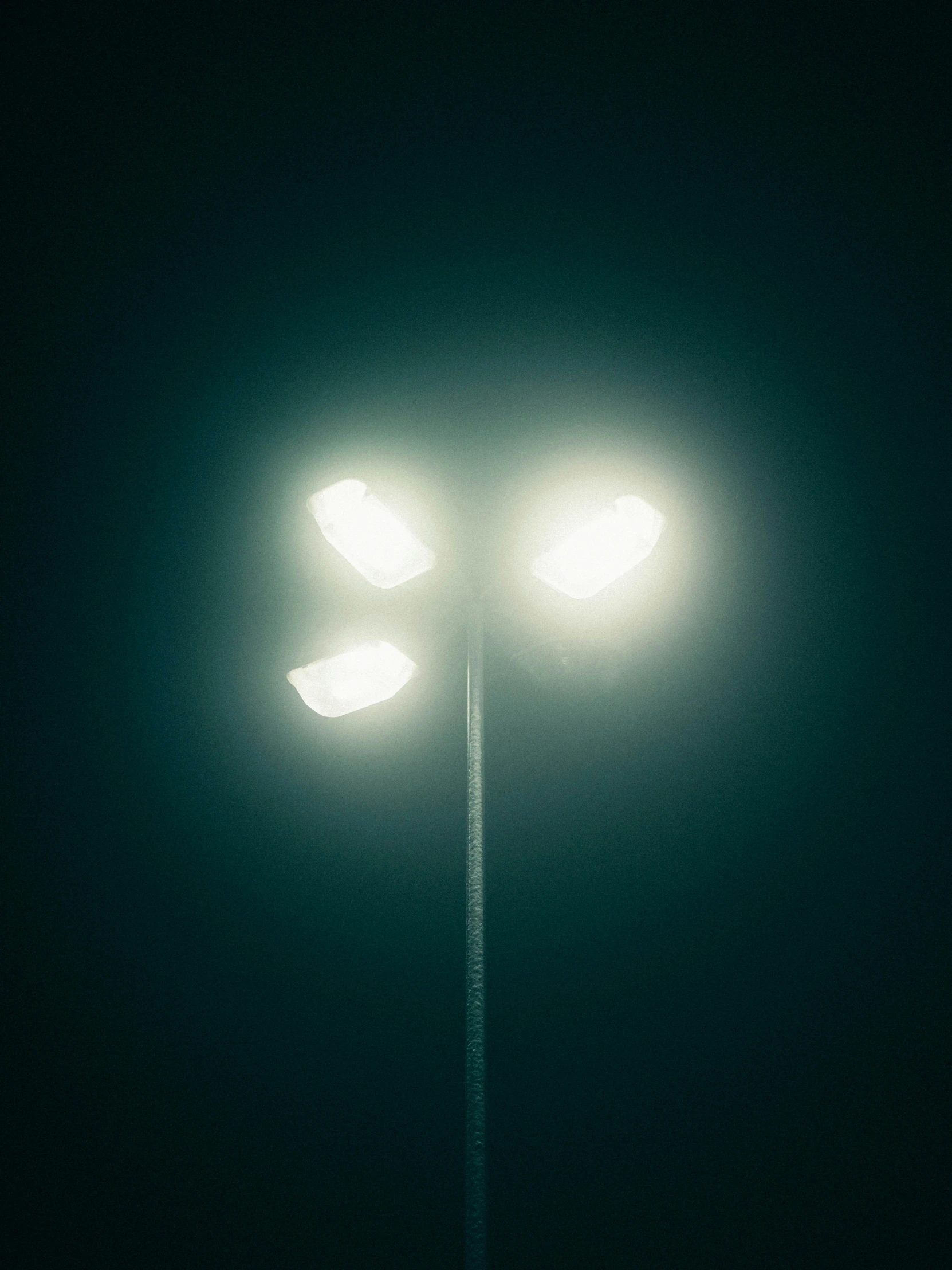 two streetlights shining green in the dark