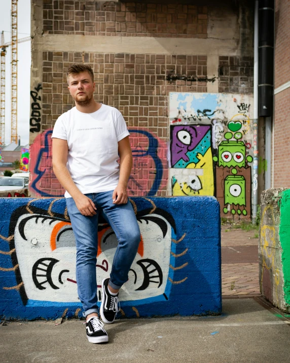 a man sitting on the side of a building in front of grafitti