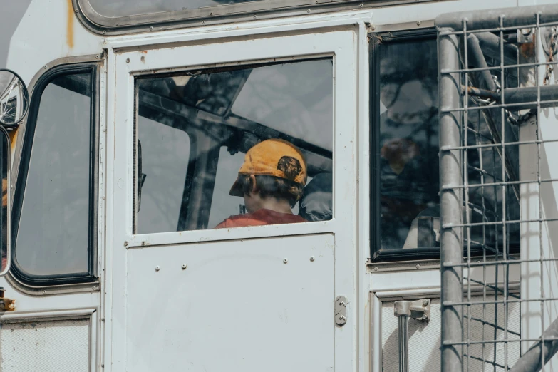 a worker sitting in the side of a truck wearing a yellow helmet