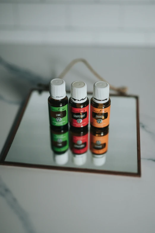 three small bottles of essential oils are on a mirror