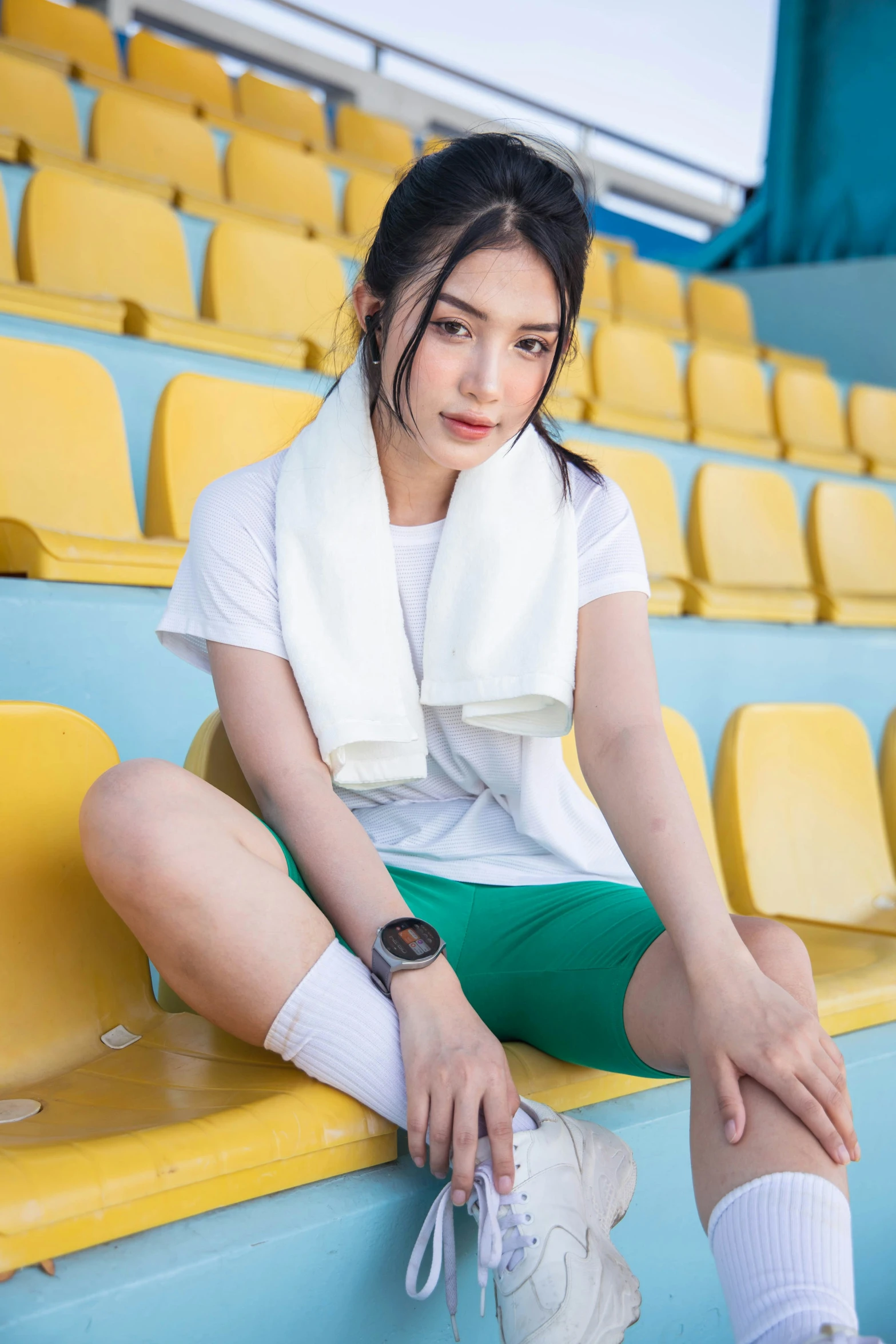 a woman wearing green shorts sitting on the bleachers