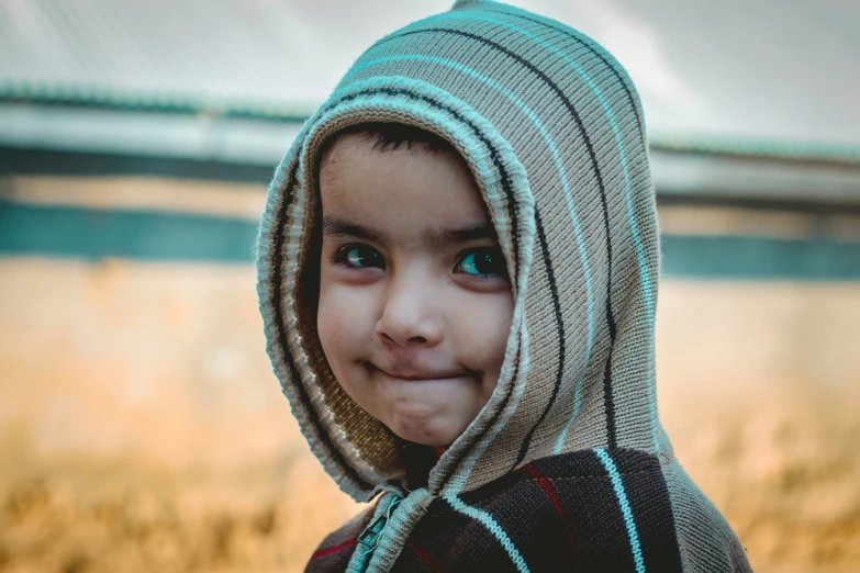 a child in a knitted hooded jumper posing for a po