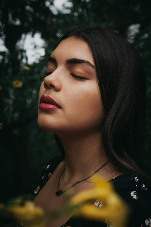 a woman with long hair and eyes closed stares into the distance