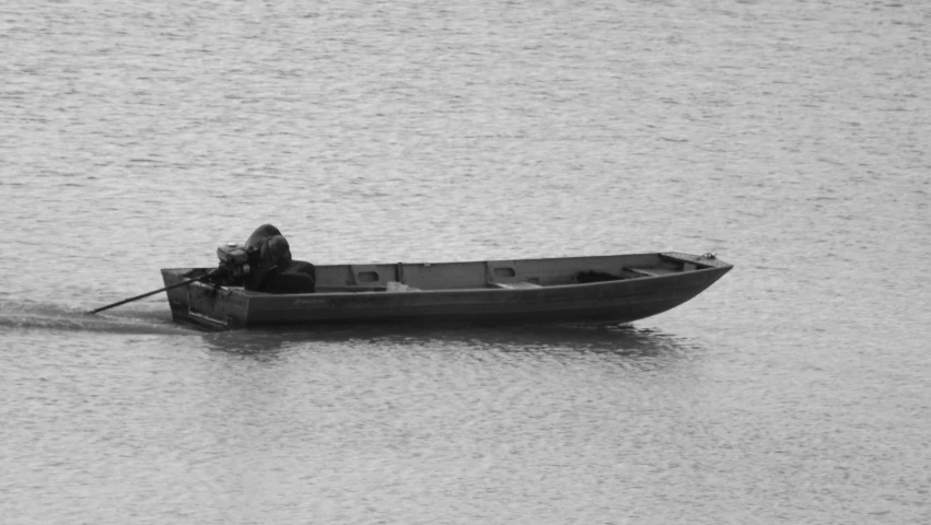 black and white pograph of man sitting in rowboat out on lake