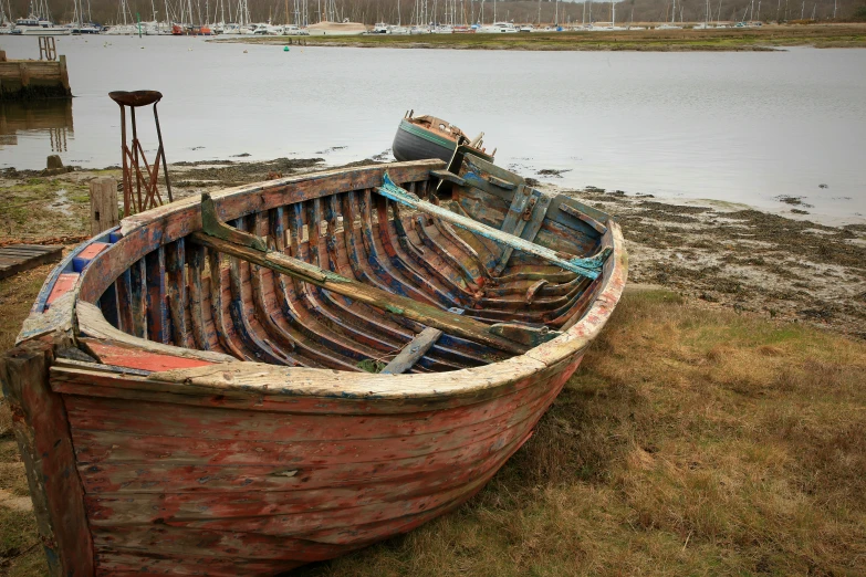 an old wooden boat sitting on the side of a river