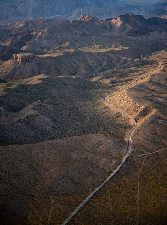 an aerial view of the desert and mountains with a road winding through it