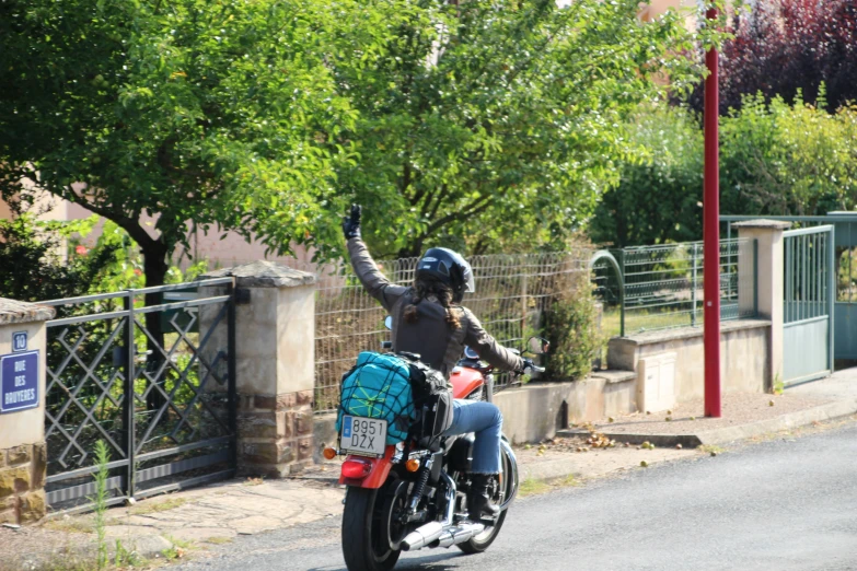 a person in black is riding a motorcycle with a blue trunk case on the back