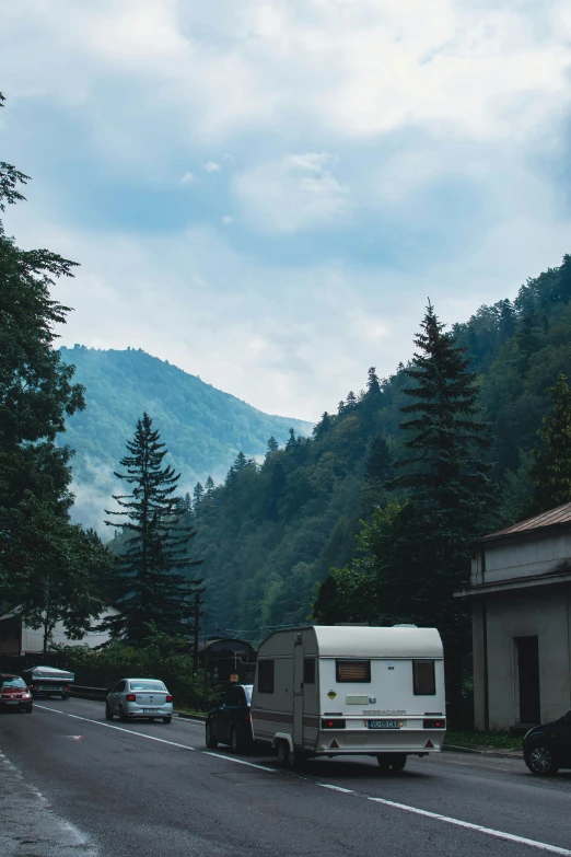 a very narrow road with many cars and caravans in front of a hill