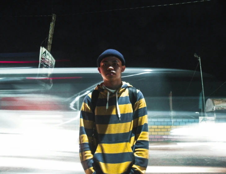 a person standing in a parking lot wearing a striped hoodie