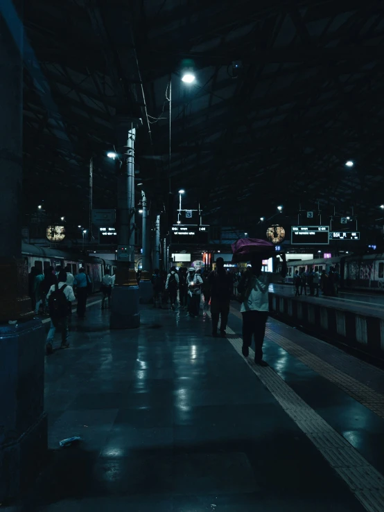 a man with an umbrella walks on a walkway in the city at night