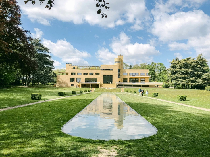 the reflection of an orange brick house in a pond at the end of a walkway