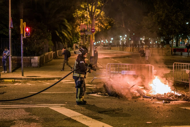 a person with a fire hose standing in front of a burning hydrant