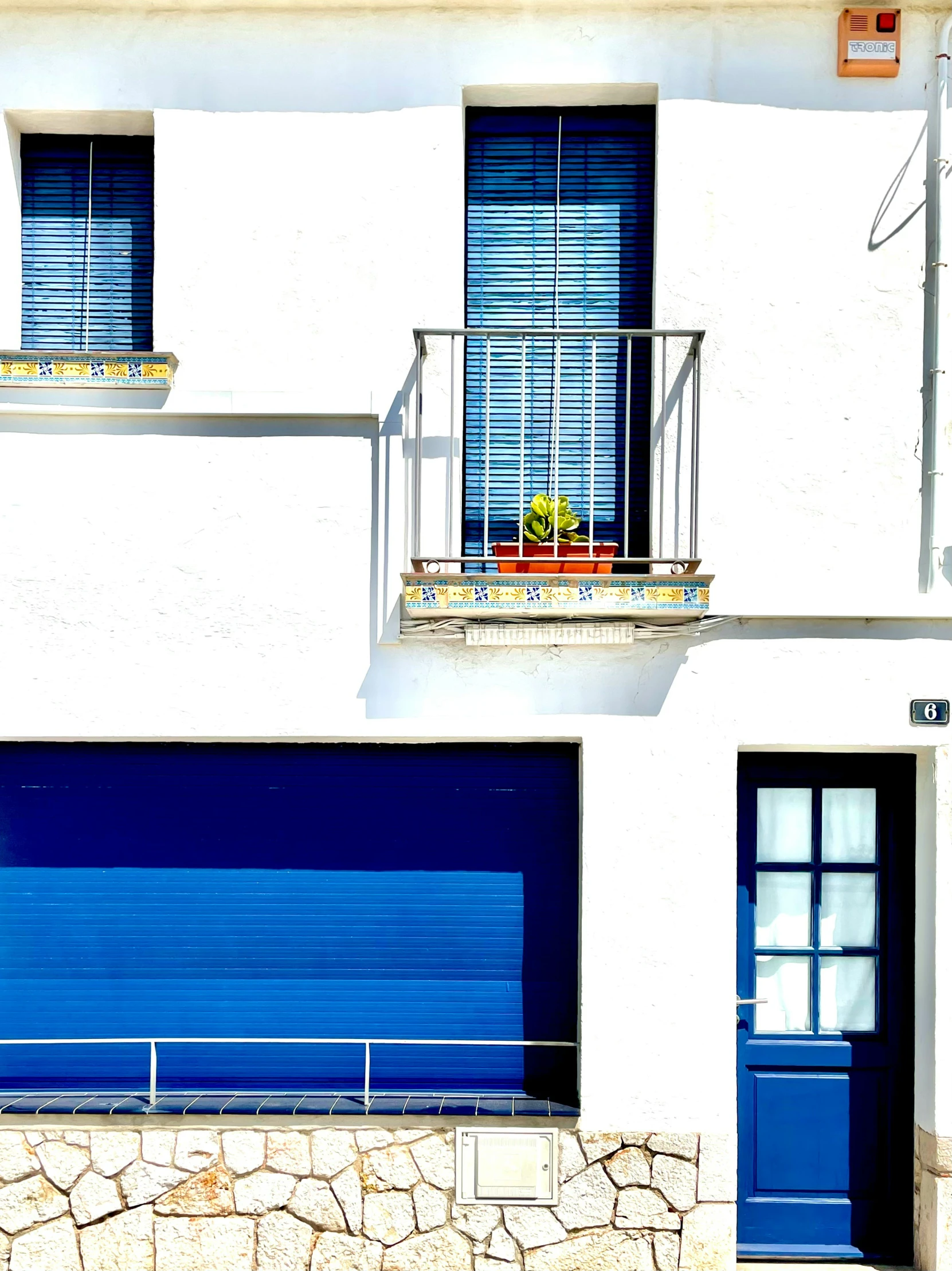 a blue roller up garage door is beside a white building