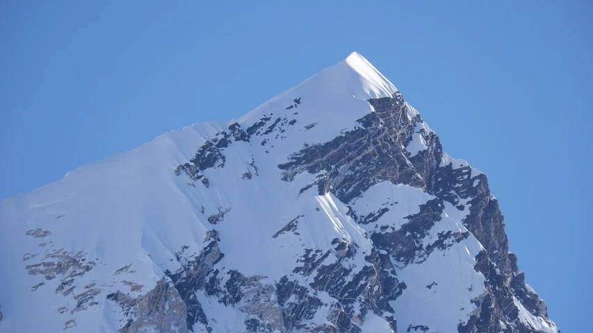 a snow - covered mountain has tall jagged rocks on it