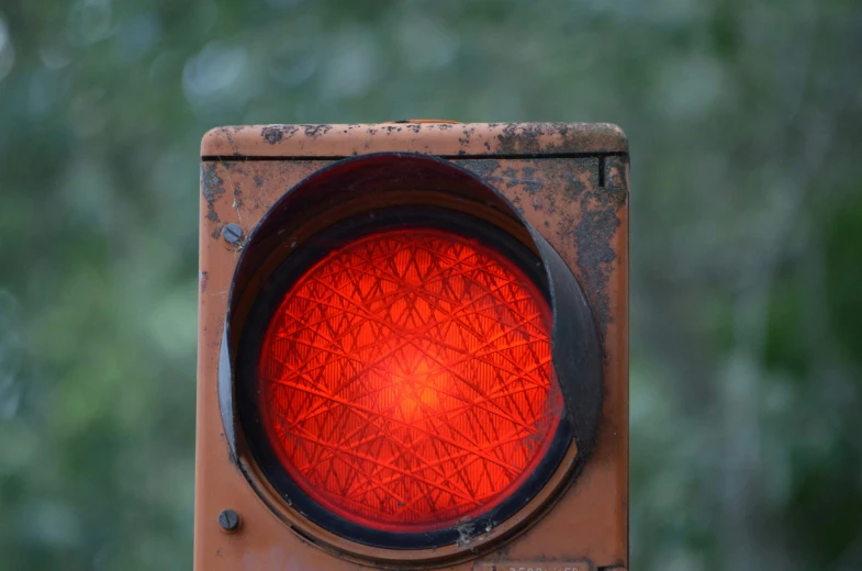 the stoplight is made of metal and has an orange circle on it