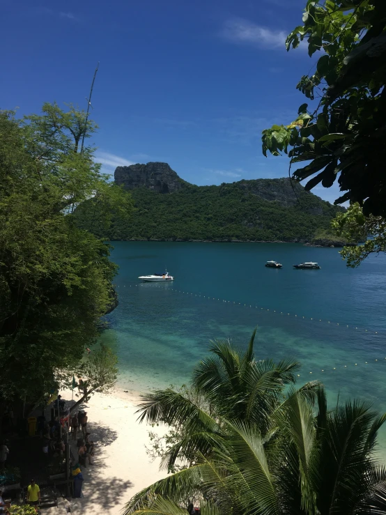 several boats anchored in the blue water at an island