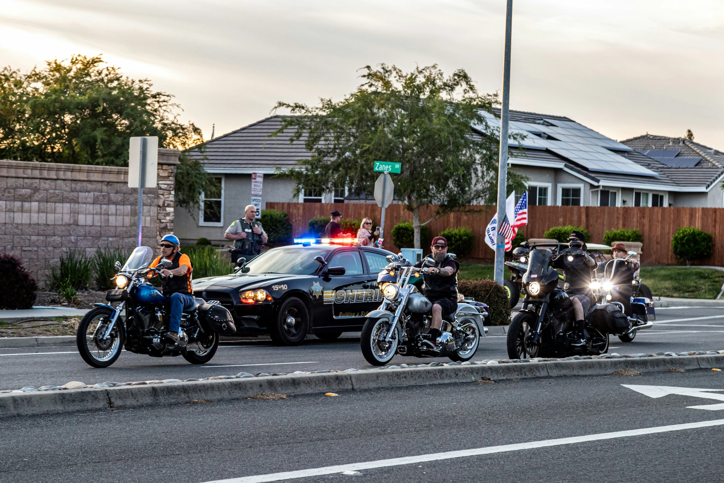 five cops riding motorcycles through a street near houses