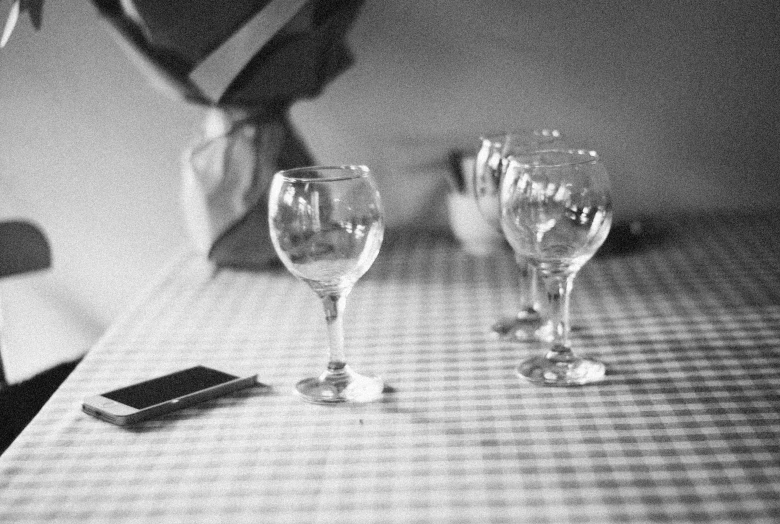 a person's hand reaching into wine glasses on a table