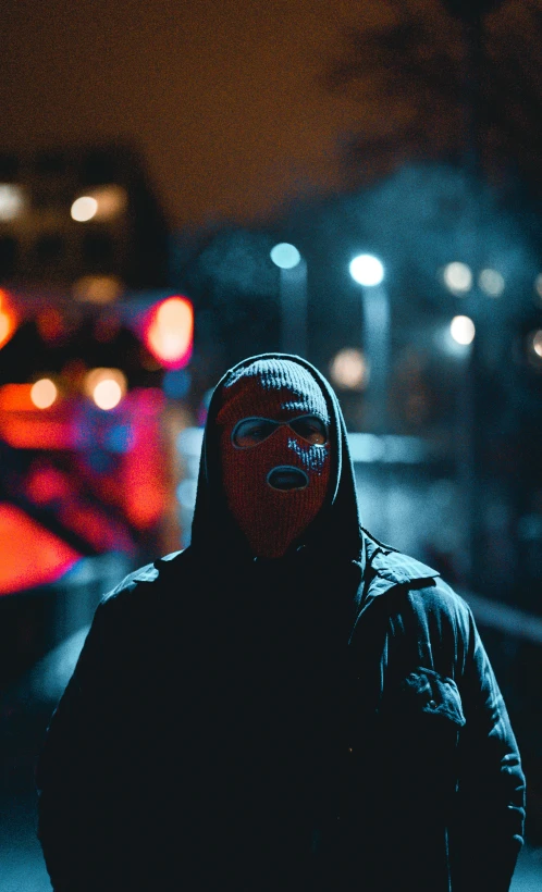 a man wearing a hooded jacket is standing on a city sidewalk