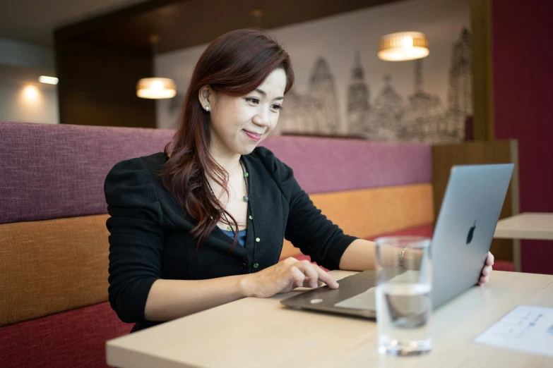 a woman sitting at a table with a laptop computer