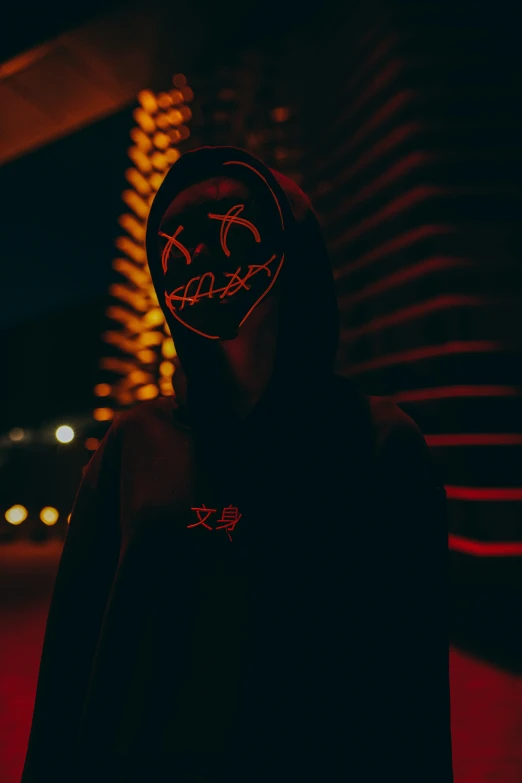 a person wearing a dark colored hoodie and a scary mask