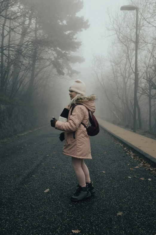 a little girl walking down the road in the fog