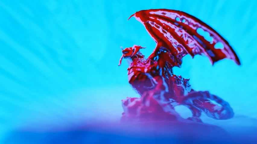 a figurine of a winged dragon with a long red tail on a blue background