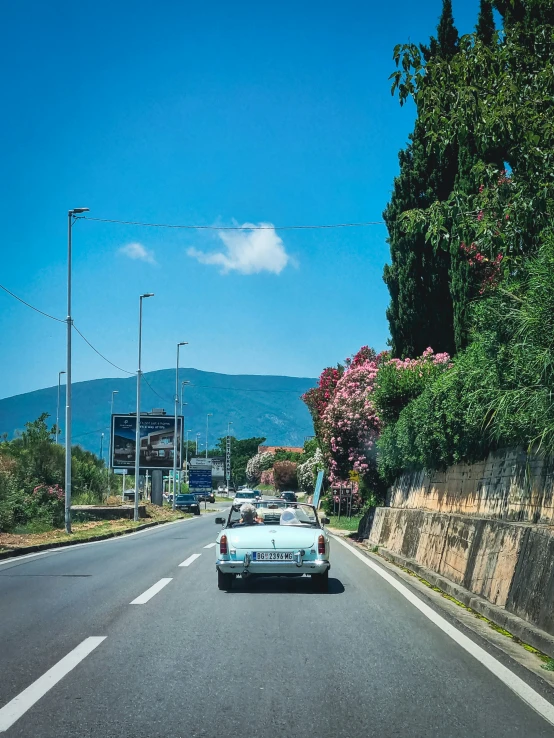 an old car sits parked on the side of the road