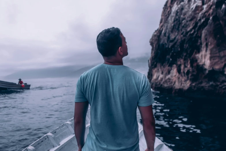 a man walking down the side of a boat towards some mountains