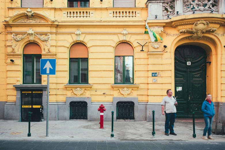 two people standing on the corner of the street near a fire hydrant