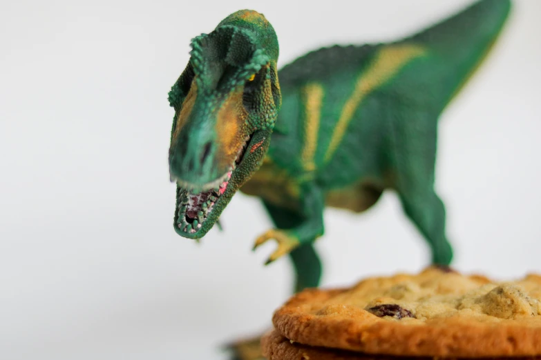a cookie sitting next to a plastic dinosaur figurine