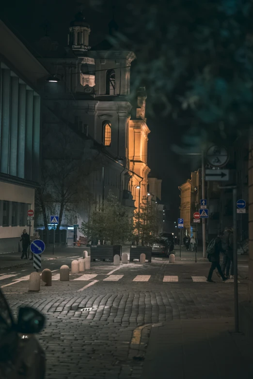 a man crossing a street at night in front of a large building