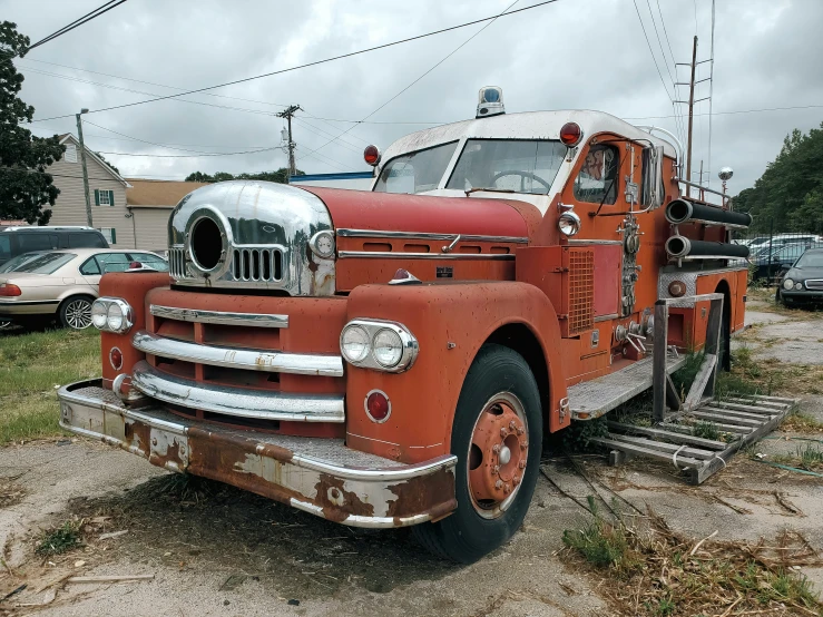 an old red firetruck is parked in the dirt