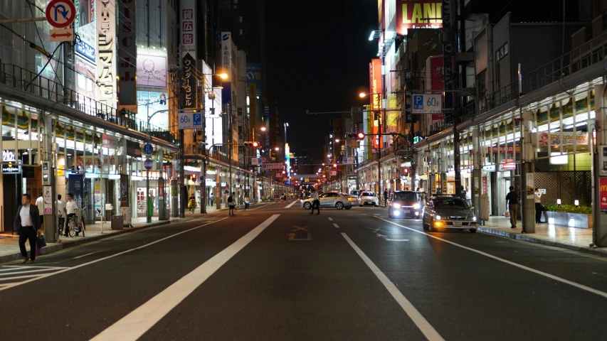 a busy city street at night with buildings, cars, and signs