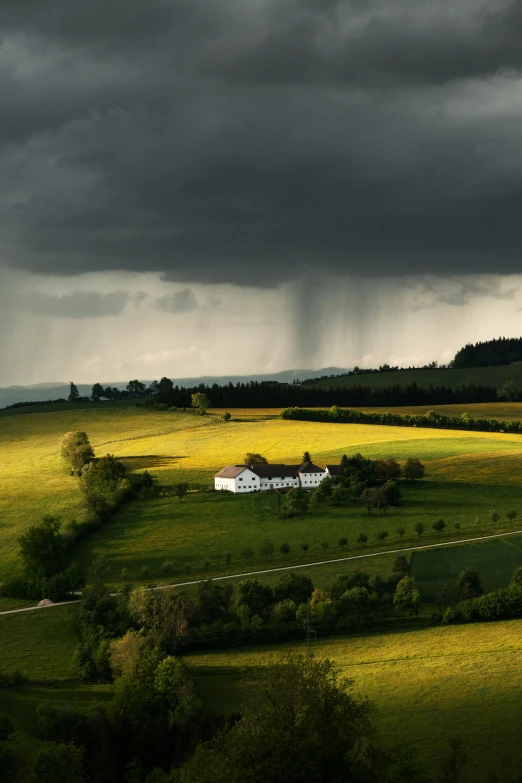 a farm house is in a grassy field with a dark sky above