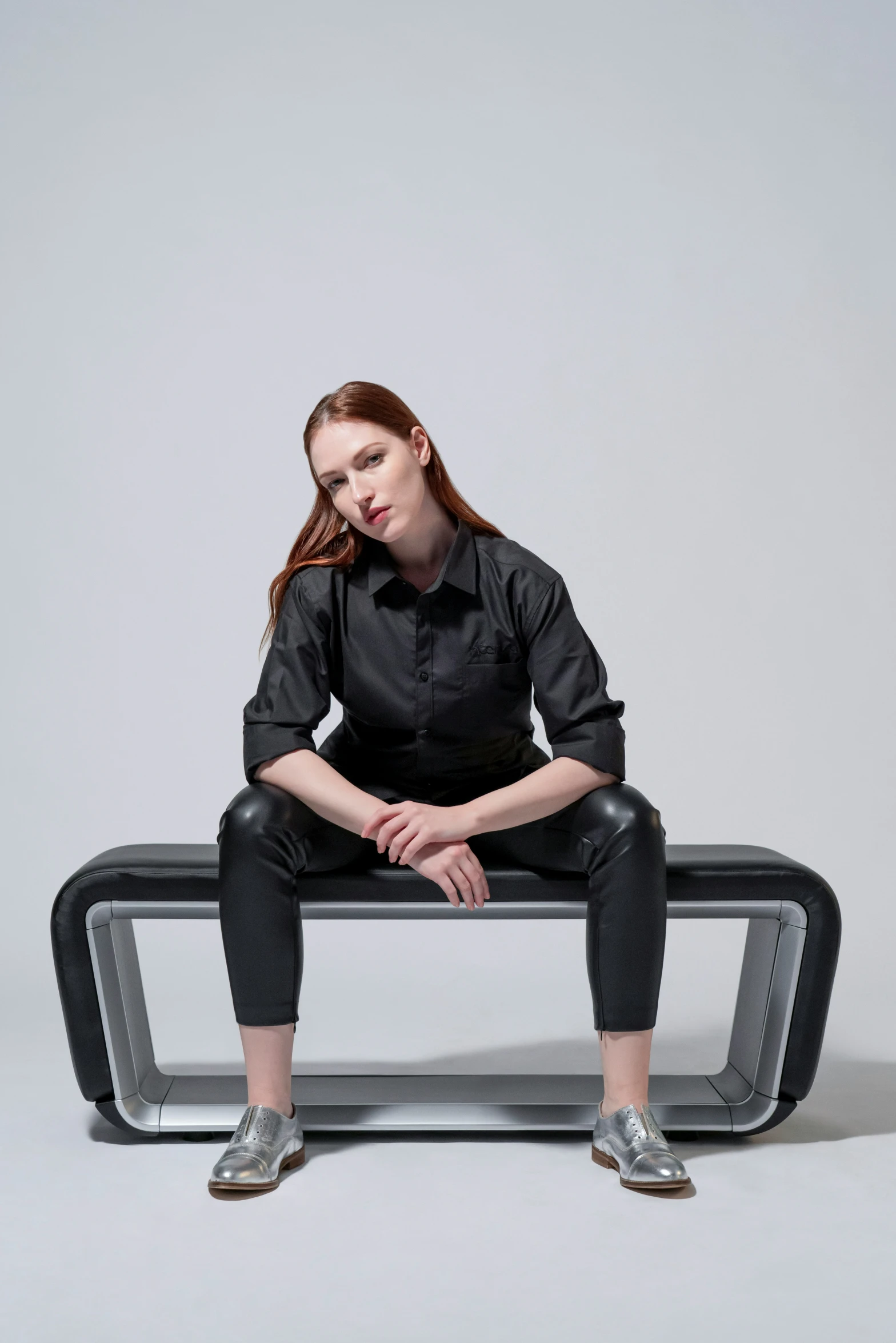 a woman sitting on a bench wearing black pants