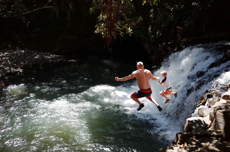 people jumping a waterfall on their own