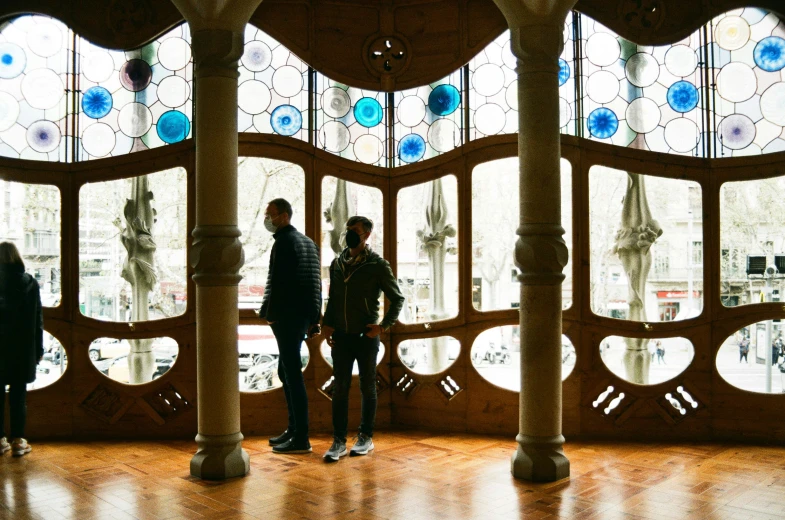 three people standing in an ornate room with multicolored glass