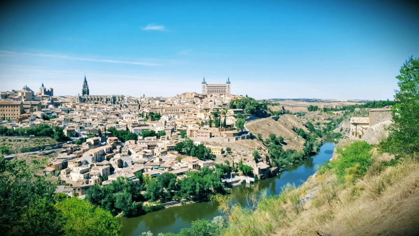 old buildings and trees stand on a hill overlooking a river